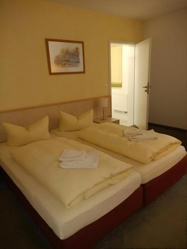 two beds in a hotel room with towels on them at Pension Am Seeberg in Alt Zeschdorf