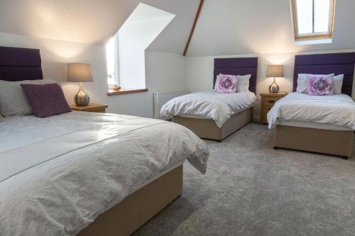 two beds in a bedroom with purple and white at Sunset View in Innellan