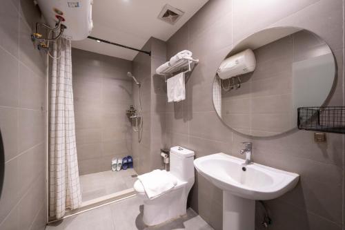 une salle de bain avec un lavabo, des toilettes et un miroir dans l'établissement Tianhe Residence, Shanghai, à Shanghai