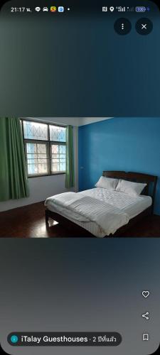 een slaapkamer met een bed met een blauwe muur bij Italay in Krabi town