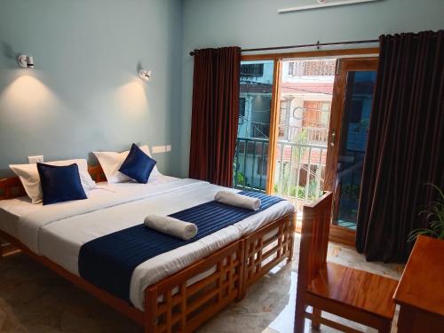 a bedroom with a bed with blue pillows and a window at Casa Branca Retreat &Hub in Varkala