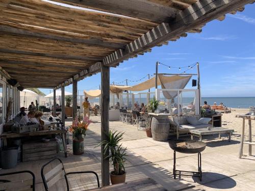 Un patio con gente sentada en mesas en la playa. en Pakhuis Achter - Rustig gelegen vlakbij Amsterdam & Zaanse Schans, en Wormerveer