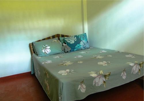a small bed in a room with flowers on it at Knight's Dale Knuckles Holiday Bungalow in Kandy