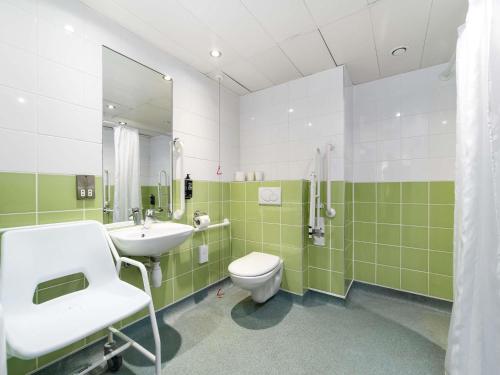 a green and white bathroom with a sink and a toilet at ibis budget Southampton Centre in Southampton