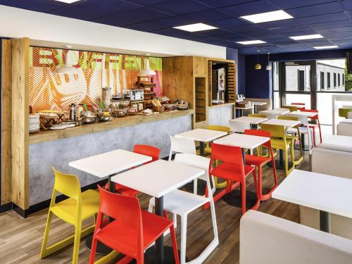 a restaurant with white tables and colorful chairs at ibis budget Southampton Centre in Southampton