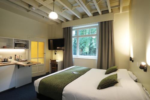 a hotel room with a large bed and a kitchen at Aparthotel Acacia in Eeklo
