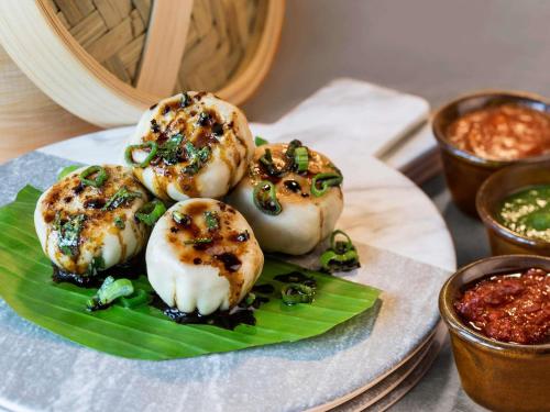 バンガロールにあるibis Bengaluru City Centre - An Accor Brandの緑の葉の上にホタテ貝が乗った料理の皿