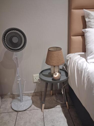 een slaapkamer met een tafel met een ventilator naast een bed bij TripleM comfort zone in Windhoek