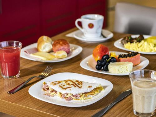ペトロリーナにあるibis Petrolinaの食べ物や飲み物の皿が置かれた木製のテーブル
