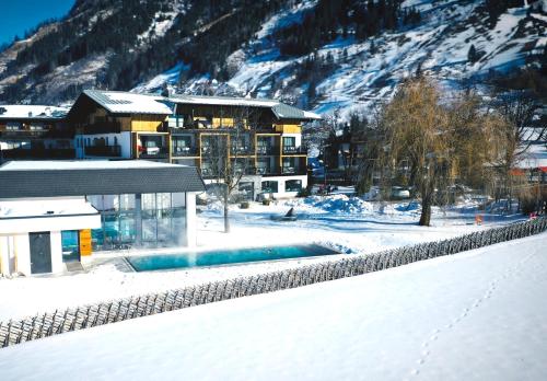 ein Gebäude mit einem Pool im Schnee in der Unterkunft Rauriserhof 4 Sterne Superior in Rauris