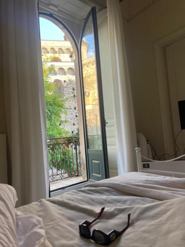 eine Brille, die auf einem Bett vor einem Fenster liegt in der Unterkunft Lyberty in Randazzo