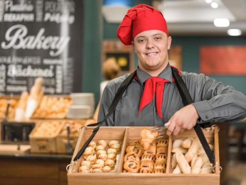 a man holding a box of pastries in a bakery at Mercure Budapest City Center in Budapest