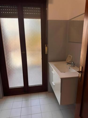 a bathroom with a sink and a sliding glass door at Casa Aris in Staranzano