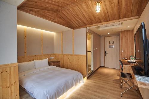a bedroom with a bed and a desk and a television at Chillax Inn 知樂愛河館 in Kaohsiung
