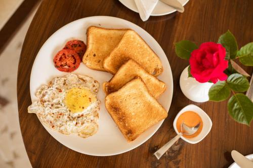 a plate of breakfast food with eggs toast and tomatoes at Spellmount - Himalayan View Infinity Pool Resort In Kausani in Kausani