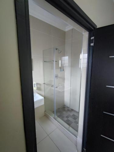 a glass shower in a bathroom with a toilet at 33onBazley Hotel in Durban