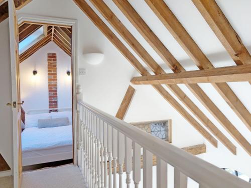 a staircase leading to a bedroom in a house with wooden beams at Courtyard Cottage, Pulborough in Pulborough