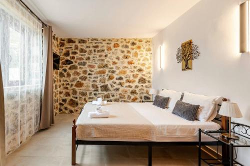 Un dormitorio con una cama y una pared de piedra. en Cassiopea Guest House Evia Greece, en Nerotriviá