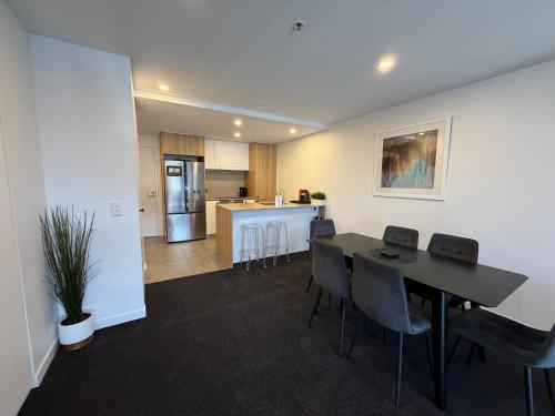 a living room with a table and chairs and a kitchen at Midnight Luxe 2BR 2Bath Apartment 507 in the heart of Braddon L5 Views Pool Sauna Gym Wifi in Canberra