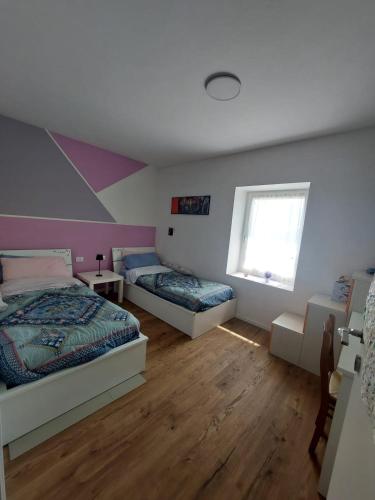 a bedroom with two beds and a window at Gemma del Lagorai in Torcegno