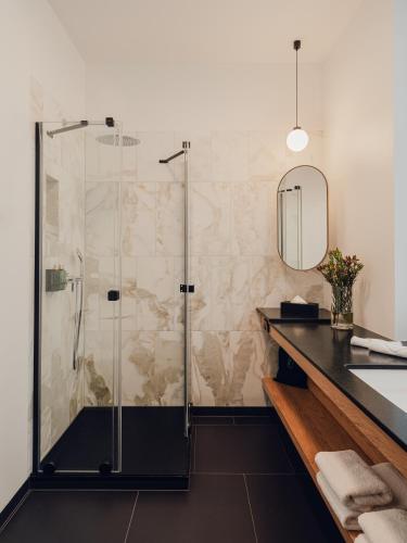 a bathroom with a shower with a sink and a mirror at Flaner Hotel, WorldHotels Crafted in Warsaw