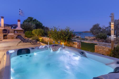 a jacuzzi tub with a view of the water at Syros Sun Beach Villa in Vari