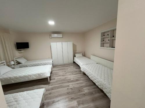 a room with three beds and a tv in it at Prenociste-apartmani Laki S in Kula