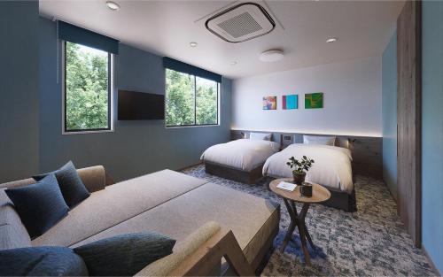 Un dormitorio con dos camas y un sofá y ventanas. en Red 28, en Ito