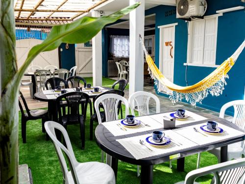 a patio with tables and chairs and a hammock at Recanto D'Ajuda in Arraial d'Ajuda