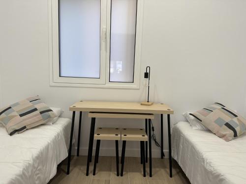 Habitación con 2 camas, mesa y ventana. en The Place Tenerife, en Santa Cruz de Tenerife
