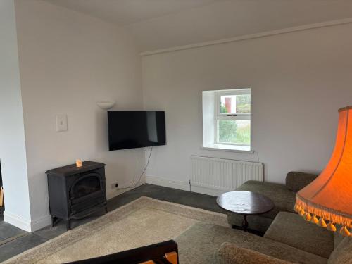 a living room with a couch and a television at Little Reds Seaview Cottage in Liscannor