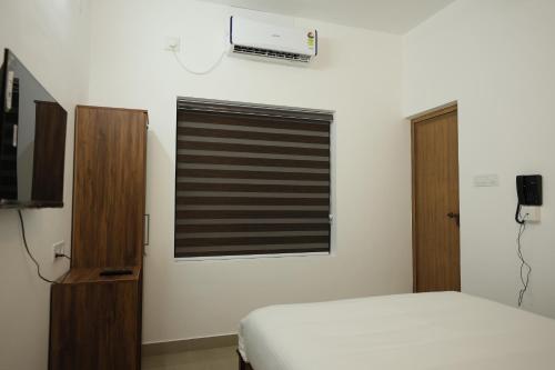 a bedroom with a bed and a window with a blind at Greens Residency in Tripunnittara