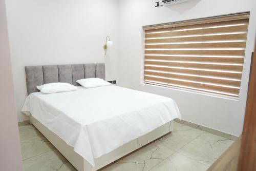 a white bedroom with a large bed and a window at Oceanus Retreat in Kottiyam