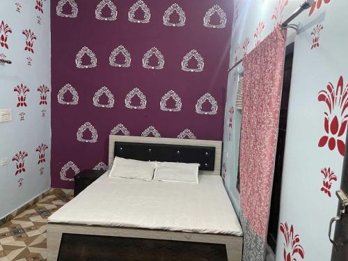 a small bed in a room with a purple wall at Hotel O The Brothers Inn in Bāra Banki