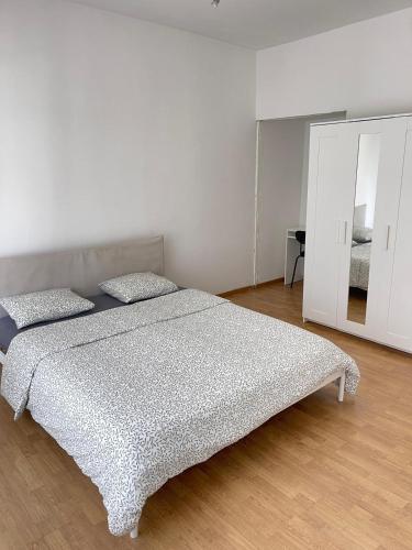 a white bedroom with a bed and a mirror at Chambre disponible in Aalst