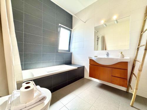 a bathroom with a tub and a sink and a toilet at Pêra Secret Garden 2 With Pool by Homing in Pêra