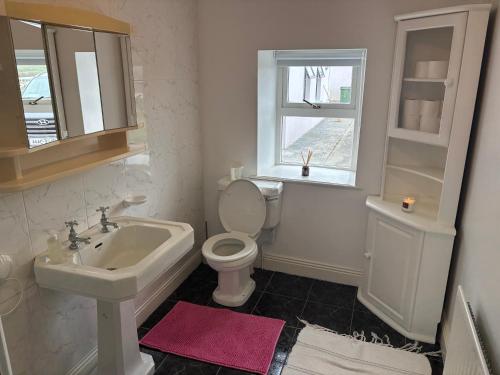 a white bathroom with a sink and a toilet at Little Reds Seaview Cottage in Liscannor