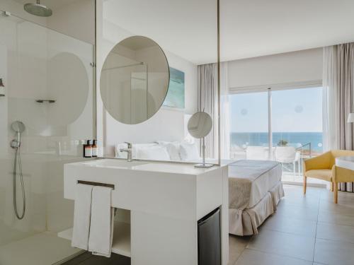 a bathroom with a sink and a mirror and a bed at Grupotel Conil Playa in Cádiz