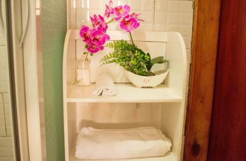 a white shelf with pink flowers in a bathroom at Cozy One Bedroom Apartment with Fast Fibre Wifi, Netflix, Hot Showers, Furnished Kitchen in Kampala