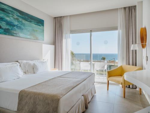 a bedroom with a bed and a view of the ocean at Grupotel Conil Playa in Cádiz