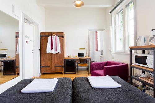 a bedroom with two beds and a pink chair at Hotelli Ville in Tampere
