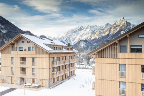 a building with snowy mountains in the background at Apartments in Hinterstoder - Oberösterreich 41145 in Hinterstoder