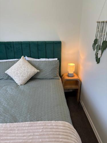 un letto con testiera verde e un tavolino con lampada di Neeri Home a Neerim South