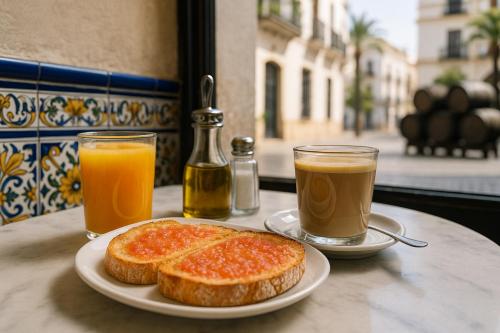 una mesa con dos rebanadas de pan y dos vasos de jugo de naranja en Casa Palacio Rufina & Jardines, en Jerez de la Frontera
