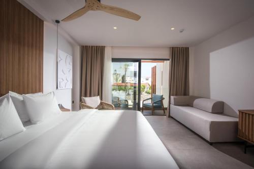 a bedroom with a large white bed and a couch at Noble Hotel & Suites - Adults Only in Gouves