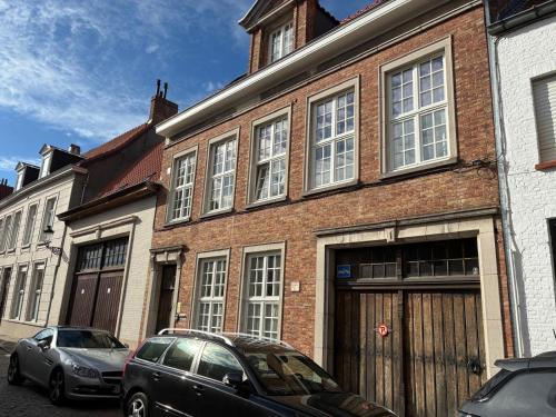 a brick building with two cars parked in front of it at Si brugge in Bruges