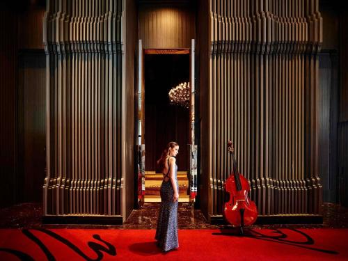 een vrouw die in een kamer staat met een gitaar bij SO/ Bangkok in Bangkok