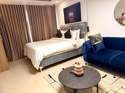 a bedroom with a bed and a blue couch at Tranquil Studio in Belrose Place, Accra in Accra