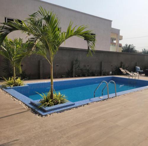 a swimming pool with a palm tree next to a building at Tranquil Studio in Belrose Place, Accra in Accra