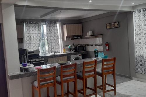 a kitchen with a bar with four chairs in it at 1 Bed Apartment Sleeps 4 with Free Parking in Kasoa